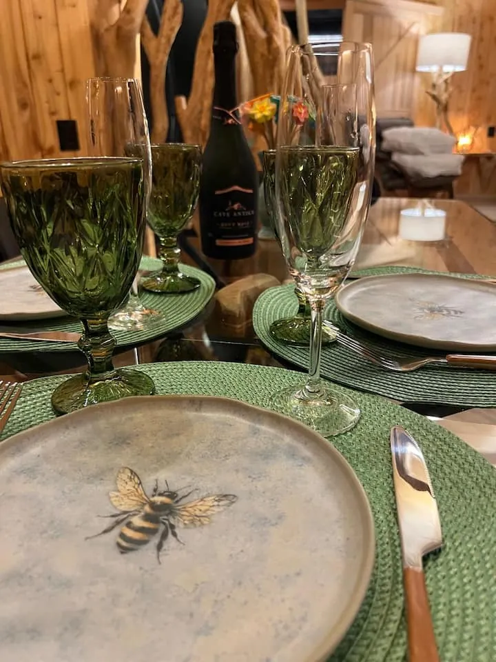 Mesa posta com taças verdes e prato com desenho de abelha