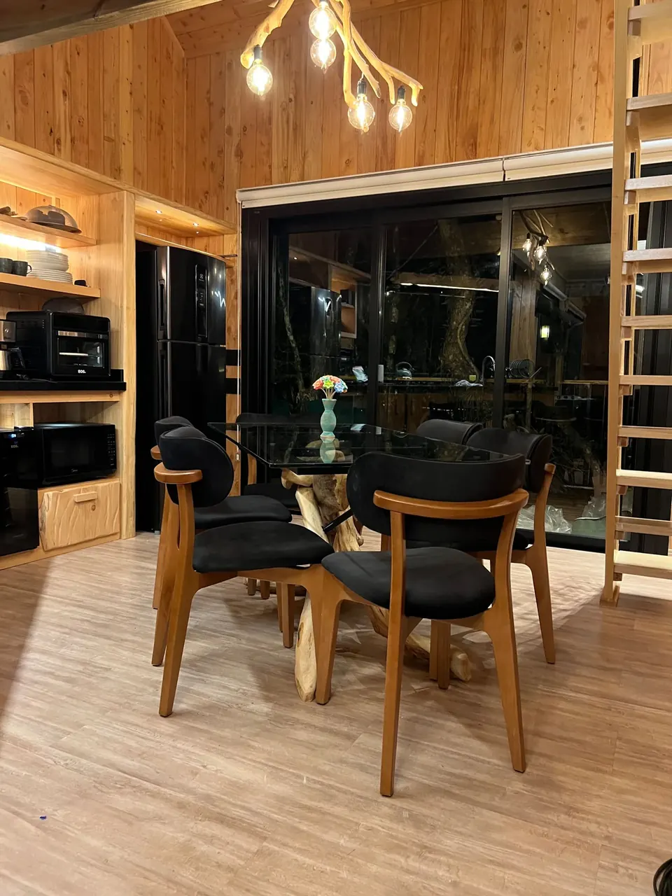 Mesa de jantar de vidro com cadeiras de madeira junto à cozinha
